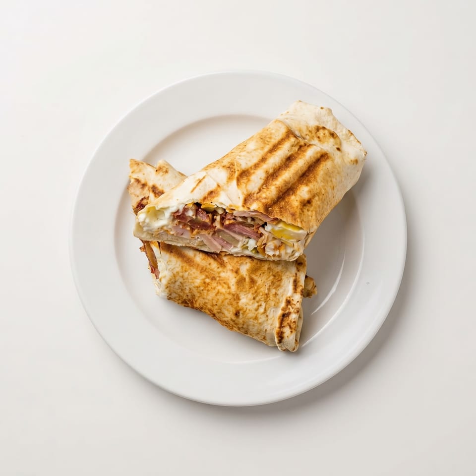 Two grilled wraps, cut in half, revealing meat, cheese, and vegetables on a white plate.
